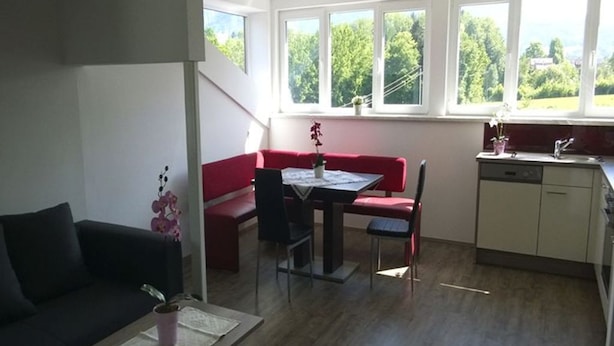Ein kompakter Wohnbereich mit Essplatz, einer Couch, einem Couchtisch und einer Küchenzeile mit Spüle und Schränken.