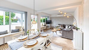 Una sala de estar moderna con comedor, ventanas amplias y televisor.