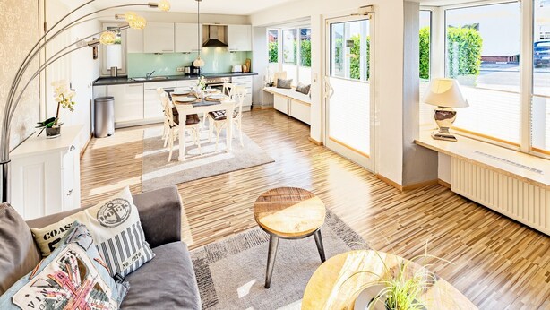 Una cocina moderna con comedor, ventanas amplias y una zona de estar acogedora con sofá y mesa de centro.