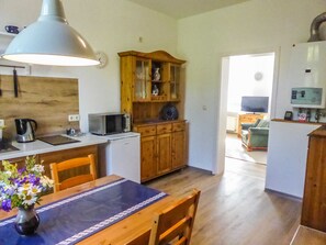 A compact kitchen with a microwave, kettle, and wooden cabinets.