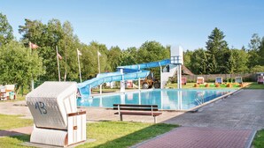 Une piscine avec un toboggan bleu, un banc et un poste de surveillance pour le sauveteur.