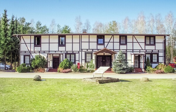 A traditional half-timbered building with a symmetrical facade, multiple doors, and a central entrance with a small porch.