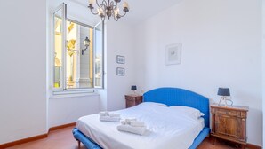 A bedroom with a large bed, a window, a chandelier, and a nightstand. - Pet friendly apartment in Rapallo -GE- (Rapallo -GE-)