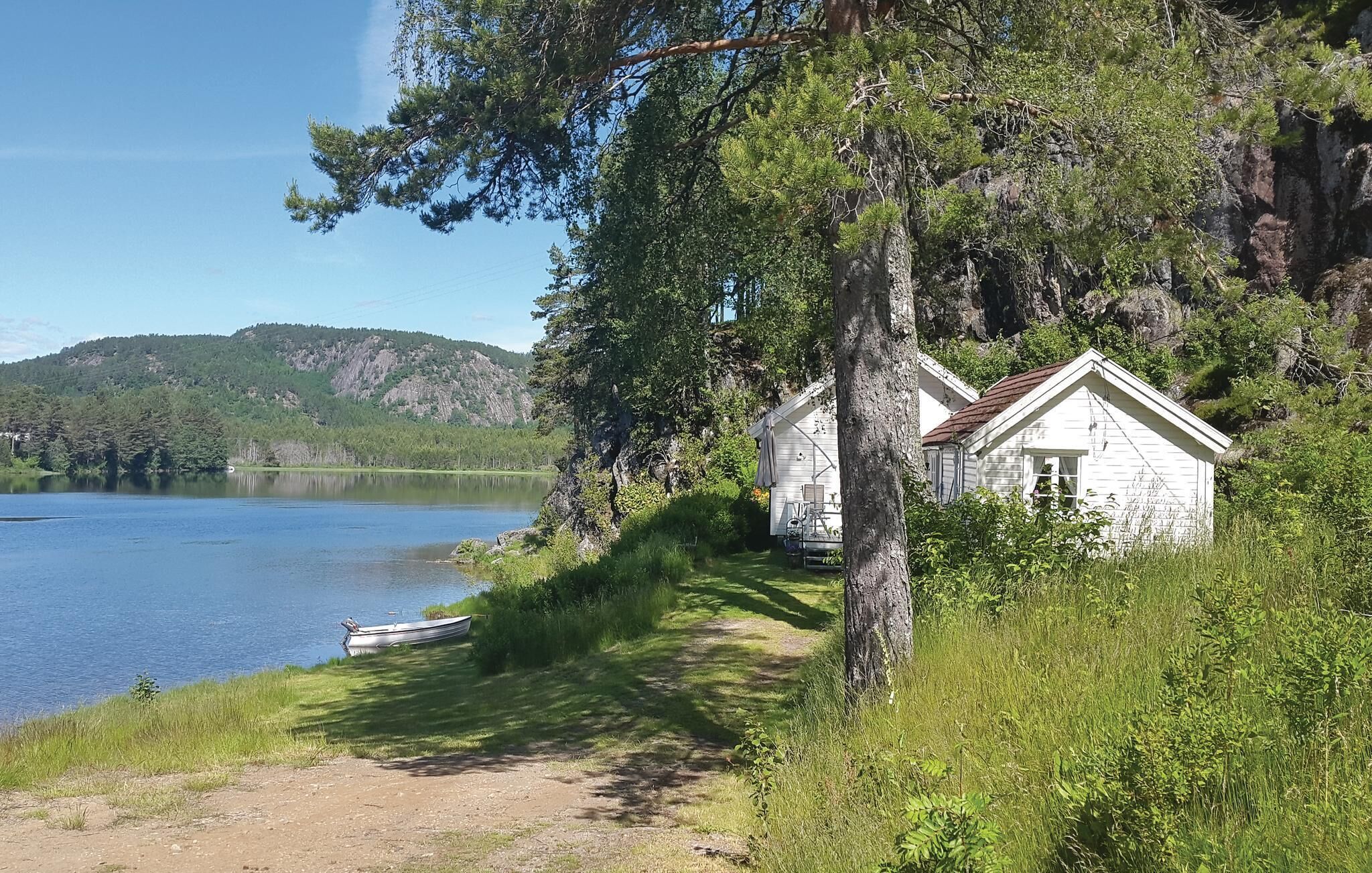 En stuga vid en sjö med fri utsikt över vattnet och den omgivande skogen.