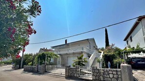 A two-story house with a stone facade, a white balcony, and a stone wall surrounding the property. - Holiday flat with terrace and air conditioning (Šilo)