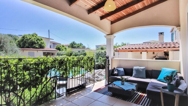 Ein überdachter Balkon mit einer Couch, einem Tisch und einer Pendelleuchte.