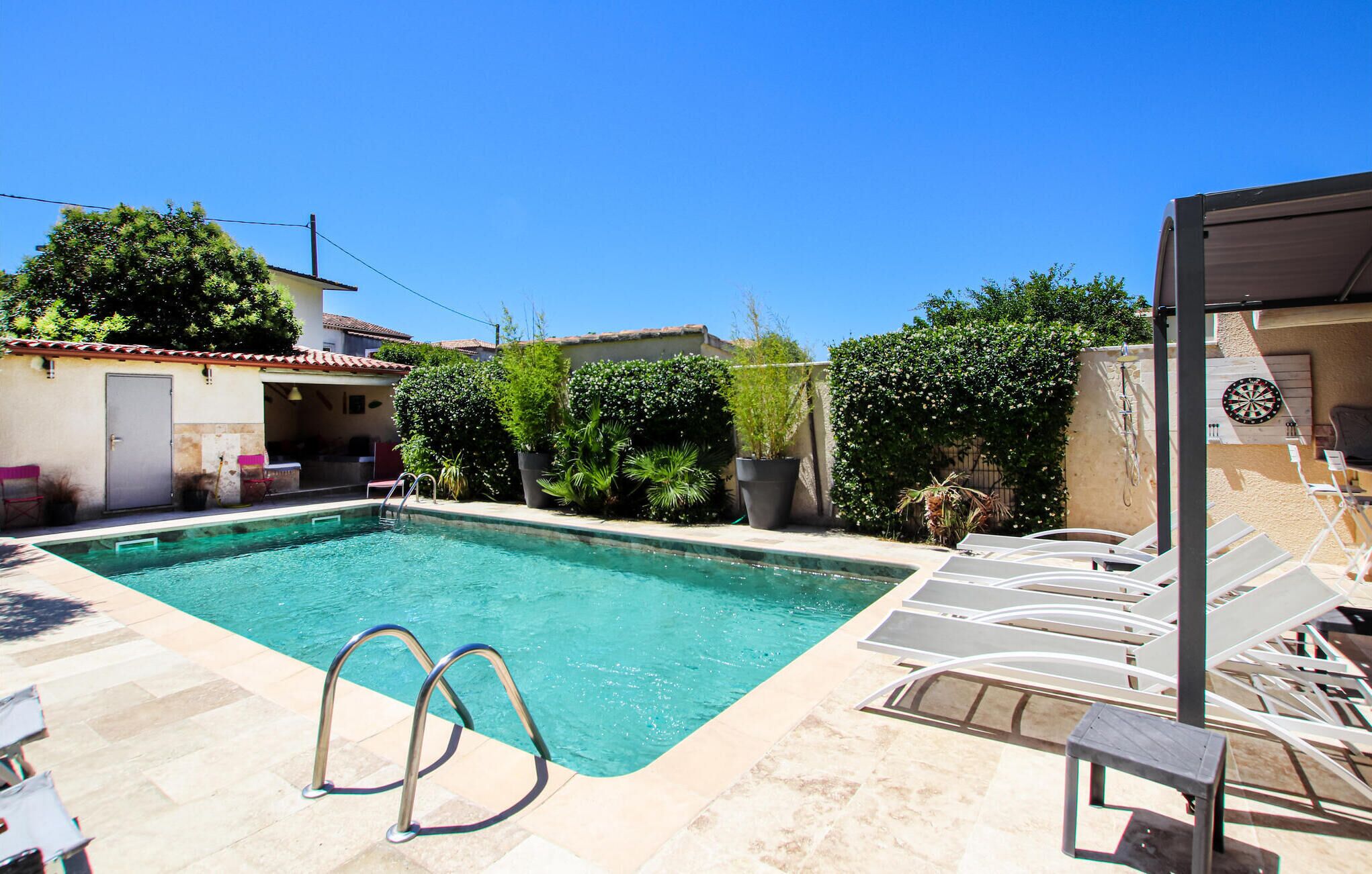 A swimming pool with clear water, surrounded by lounge chairs and potted plants.