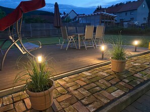 A wooden deck with outdoor furniture, potted plants, and a pergola with umbrellas. - Vacation apartment Sporn, Germany (Edertal)