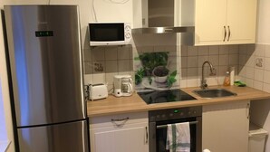 Una cocina moderna con electrodomésticos de acero inoxidable, microondas, cafetera y fregadero.