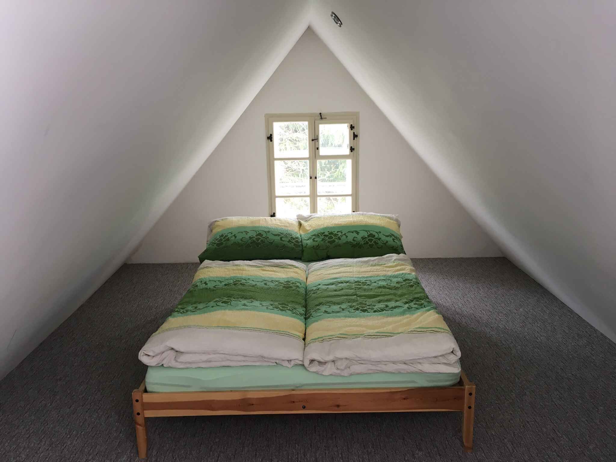 Un lit simple dans une chambre avec un plafond en pente et une fenêtre.