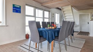 Ruokailutila, jossa on sininen pöytäliina, harmaat tuolit ja puinen katto.