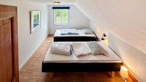 Una habitació petita i estreta amb dos llits, una finestra i una porta.