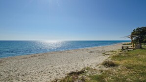 Une plage avec un ciel dégagé et une mer calme.