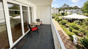 Een balkon met een tafel en stoelen, uitzicht op de omgeving en een tuin.