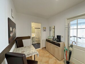 Cozinha compacta com área de refeições, cafeteira e janela com guarda-sol.