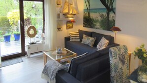 Ein Wohnzimmer mit Sofa, Couchtisch und einem Gemälde einer Strandansicht.