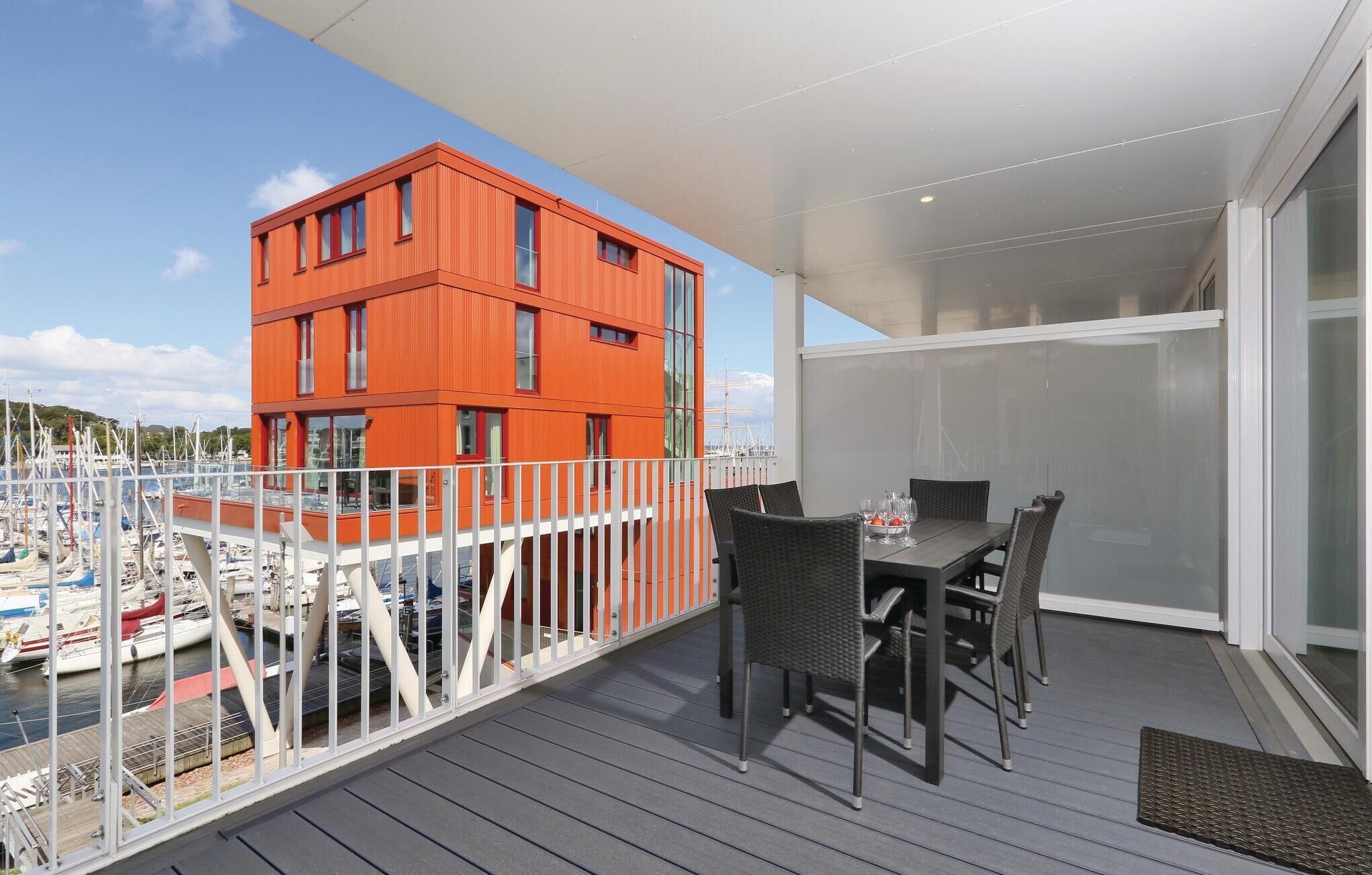 A balcony with a table and chairs, overlooking a marina with boats.