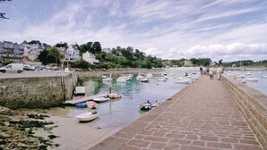 A coastal marina with boats docked, a stone walkway, and residential buildings in the background. - Amazing home in Tregunc with WiFi (Tregunc)