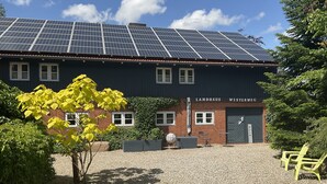 Edifici amb panells solars a la teulada, façana de maó i un rètol que diu 'Landhaus Westerweg'.