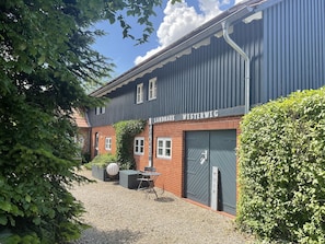 Een gebouw met een metalen buitenkant, een bakstenen gedeelte en een grindpad.