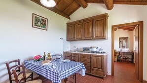 A kitchen with wooden cabinets, a tiled backsplash, and a dining area with a checkered tablecloth. - Nice apartment in Loro Ciuffenna AR (Loro Ciuffenna AR)