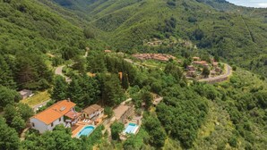 An aerial view of a hillside village with terraced houses, a swimming pool, and a winding road. - Nice apartment in Loro Ciuffenna AR (Loro Ciuffenna AR)