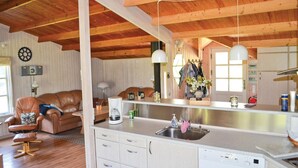 Ein gemütliches Wohnzimmer mit einem braunen Ledersofa, einem Couchtisch und einem Essbereich mit Küchenzeile und Spüle.