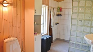 Ein Badezimmer mit Holzwänden, einem weißen Waschbecken und einer Duschkabine.