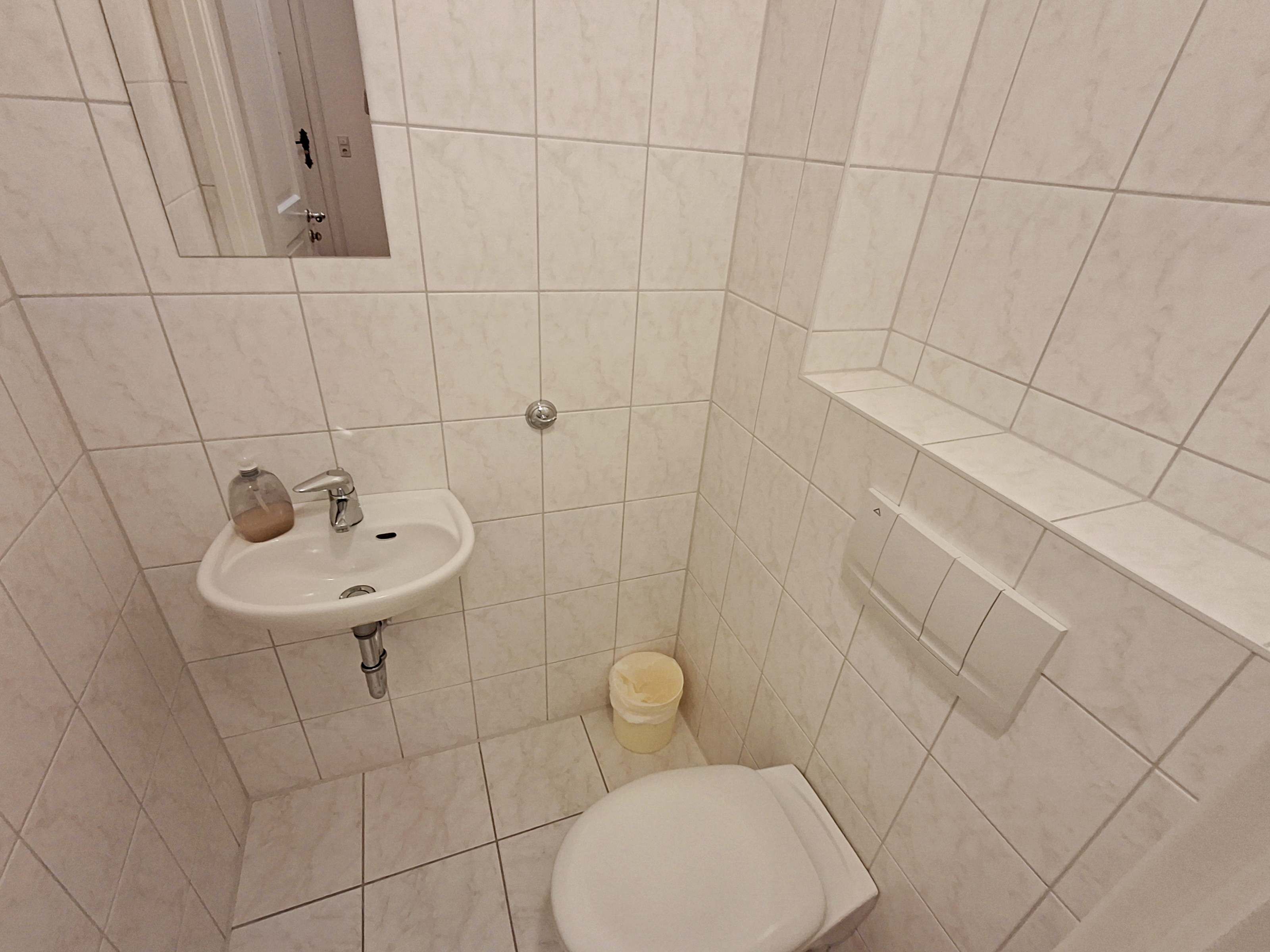Un baño pequeño con lavamanos, inodoro y espejo.