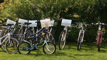 Bicicletas estacionadas numa área gramada, com árvores ao fundo.