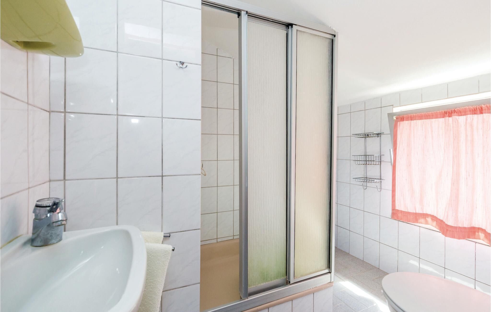 A bathroom with a white sink, a glass shower enclosure, and a toilet.