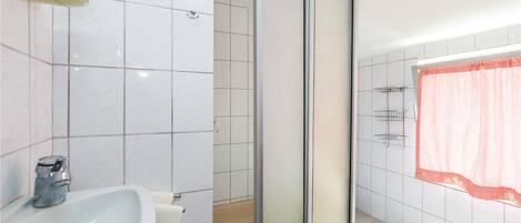 A bathroom with a white sink, a glass shower enclosure, and a toilet.