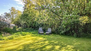 A grassy area with two wooden chairs under a tree. - 2 bedroom cozy home in Augustenborg (Augustenborg)