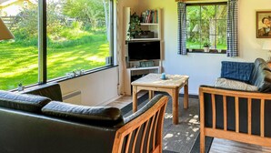 A cozy living room with a sofa, a wooden chair, a small table, and a TV on a shelf. - 2 bedroom cozy home in Augustenborg (Augustenborg)