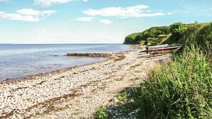 A pebbled beach with a row of boats on the right, a rocky shoreline, and a clear sky. - 2 bedroom cozy home in Augustenborg (Augustenborg)
