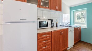 A modern kitchen with wooden cabinets, a white refrigerator, a microwave, a coffee maker, and a gas stove.