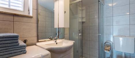 A modern bathroom with a glass shower enclosure, a double sink vanity, and a toilet.