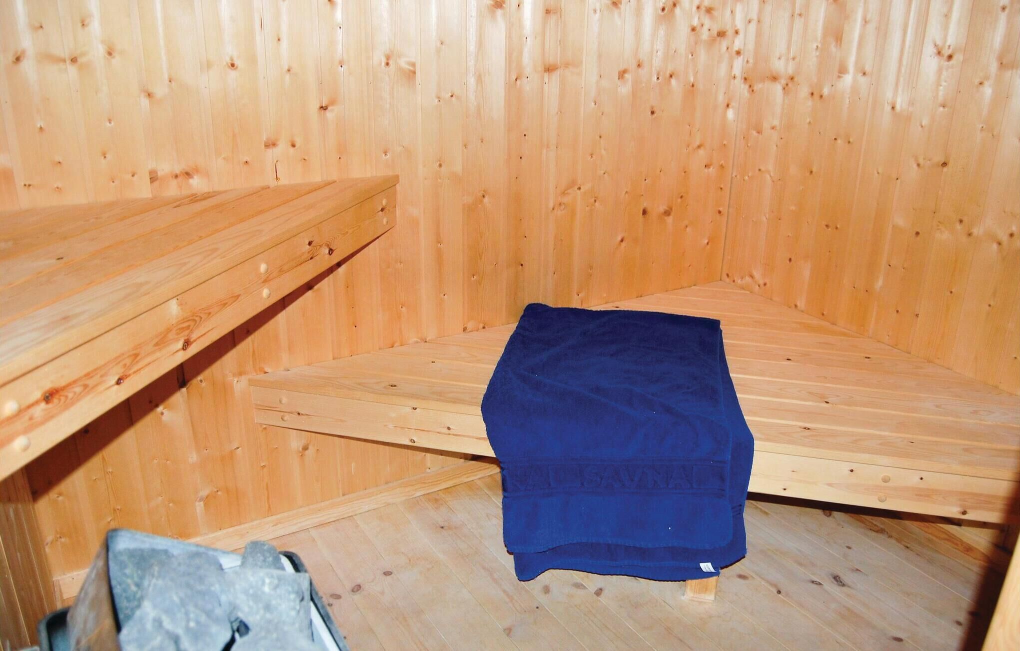 A wooden sauna room with benches and a blue towel.