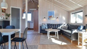 A modern interior with a dining area, a sofa, and a kitchen visible through an open door. - Nice home in Hvide Sande with sauna (Hvide Sande)