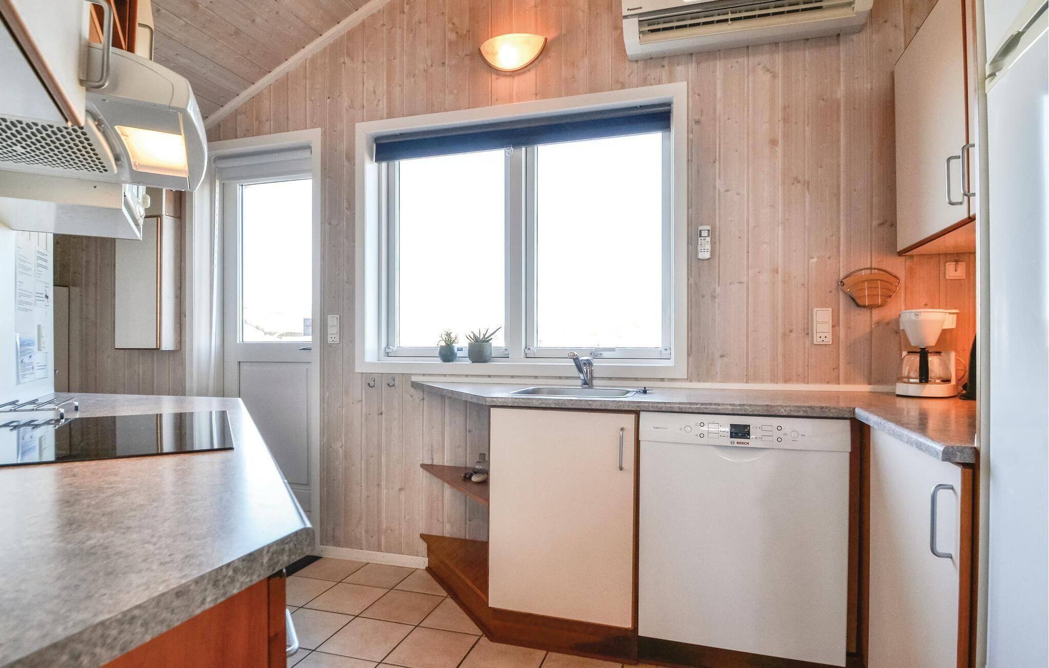 Une cuisine moderne avec un lambris en bois, une grande fenêtre, un lave-vaisselle Bosch et une machine à café.