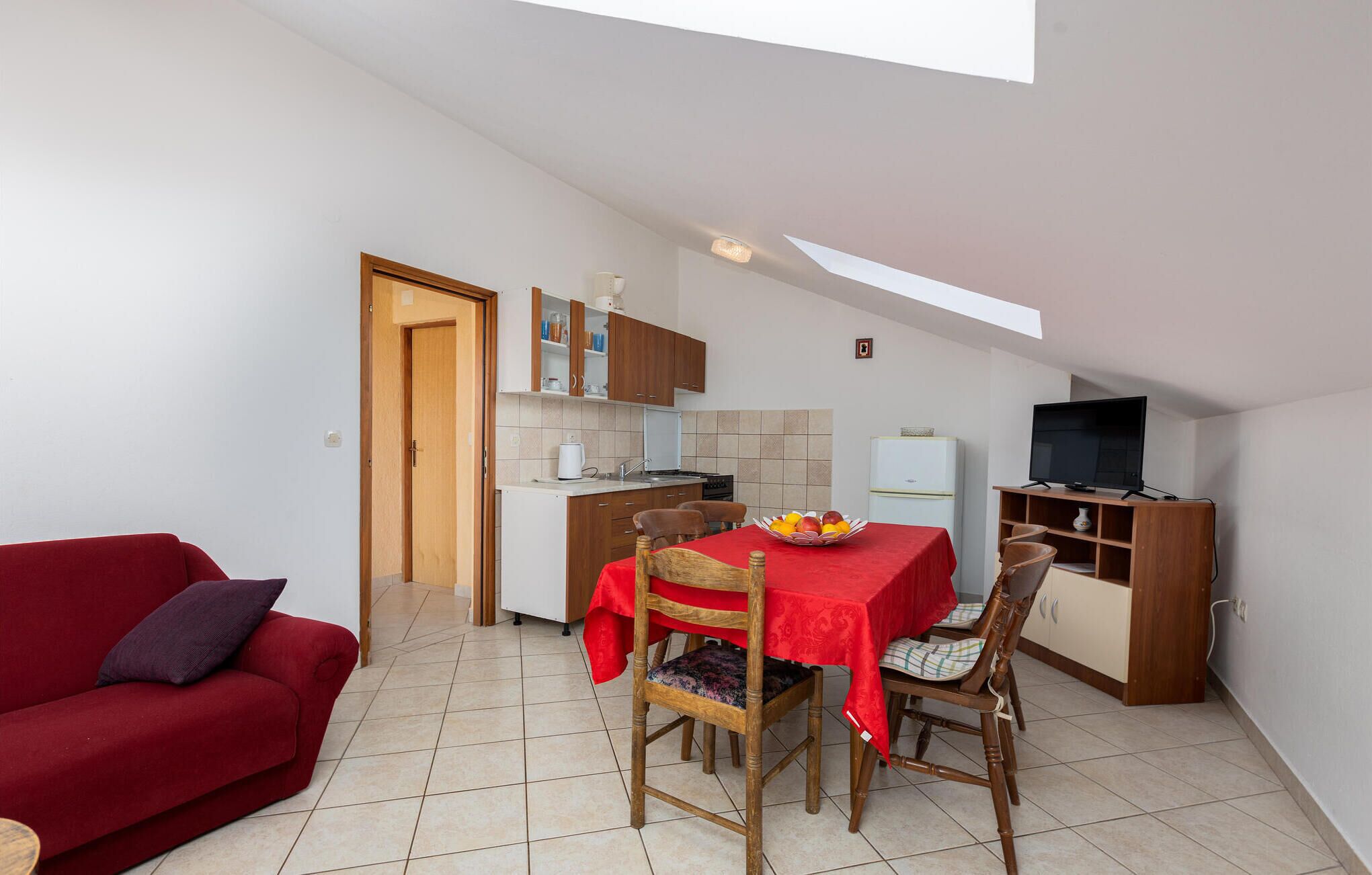 A compact living space with a dining area, kitchenette, and a red sofa.