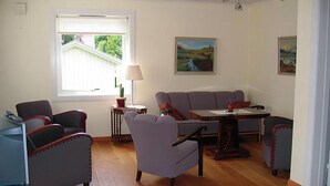 Ein Wohnzimmer mit einer Sofagarnitur, einem Esstisch und einer Lampe.