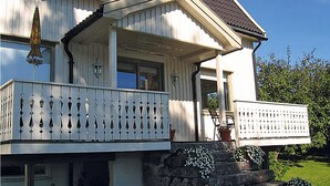 Ein zweigeschossiges Haus mit Balkon, Veranda und Natursteinfundament.