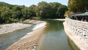 A riverside view with a stone wall and a covered seating area. - Tour Ourne Mas de Tours (Tornac)