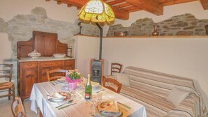 A dining area with a table set for two, a wooden cabinet, a stone wall, and a sofa. - Agriturismo La Ginestra (Città di Castello PG)