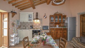 A cozy kitchen with wooden cabinets, a dining table set for two, and a built-in oven. - Agriturismo La Ginestra (Città di Castello PG)