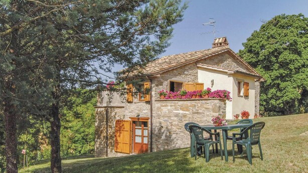 A stone house with a tiled roof, wooden shutters, and a small balcony with potted flowers. - Agriturismo La Ginestra (Città di Castello PG)
