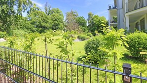 Un quartiere residenziale con un prato curato, un recinto in metallo e un edificio con un balcone.