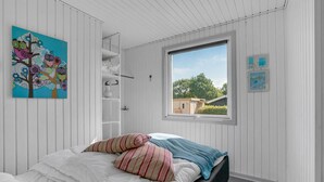 Une chambre à coucher avec un lit, une fenêtre donnant sur un beau paysage, une armoire et un tableau accroché au mur.