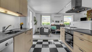 Une cuisine moderne avec un carrelage à motifs, un coin repas avec un canapé et une grande fenêtre offrant une vue sur l’extérieur.
